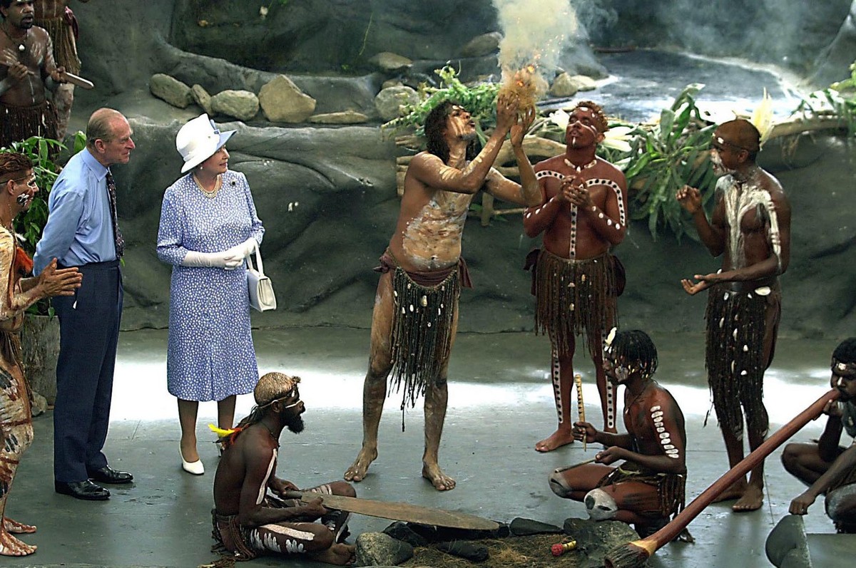 Britain's Queen Elizabeth II and Prince Philip watch as Warren Clements of the Tjapakai Aboriginal Dance Group makes fire by rubbing sticks in Cairns, Australia, Friday, March 1, 2002. (AP Photo/ ...