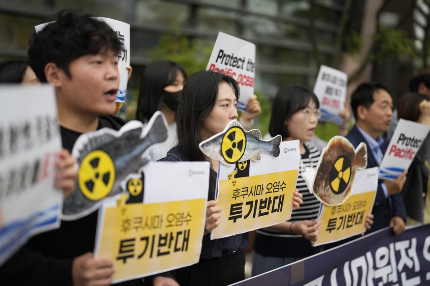 Members of civic groups hold placards at a rally to oppose the Japanese government's decision to release purified radioactive water from the Fukushima nuclear power plant, near a building in which...