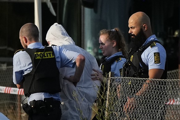 FILE - A person in a white DNA suit is taken away by police near Field's shopping center on Sunday, July 3, 2022, following a shooting in Copenhagen, Denmark.  The trial of a 23-year-old…