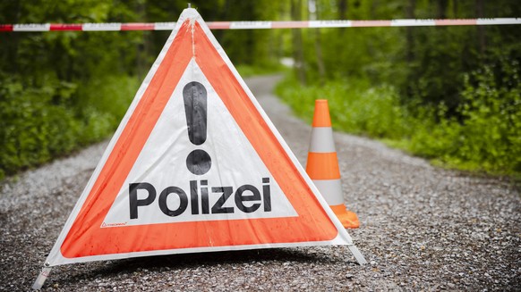 Ein gesperrter Waldweg mit einem Absperrband und einem Warndreieck mit der Aufschrift Polizei im Huerstwald, am Donnerstag, 5. Mai 2022 in Zuerich. Die Kantonspolizei Zuerich sperrte den Huerstwald im ...