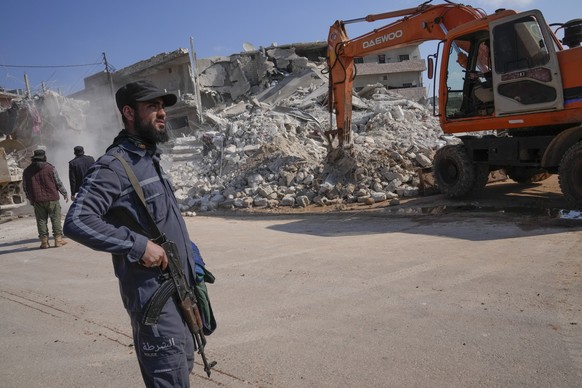 A militant of the al-Qaida-linked Hayat Tahrir al-Sham organisation stands in front of a destroyed house in Atareb, Syria, Sunday, Feb. 12, 2023. Six days after a massive earthquake killed thousands i ...