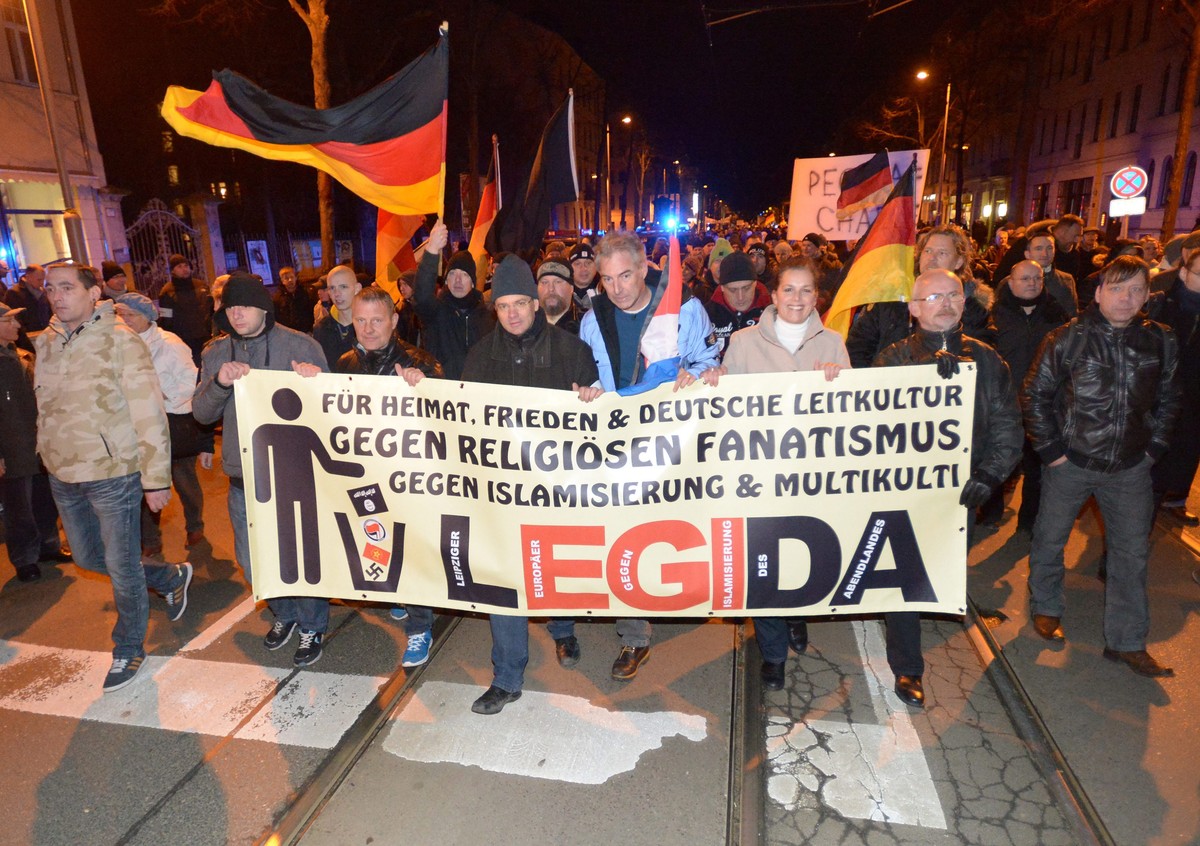 epa04557443 Members of the Anti-Islamic Legida (Leipzig against the Islamization of the West) movement carry German flags and a banner that reads 'For homeland, peace, and German Leitkultur (lit. ...