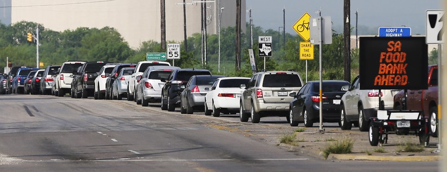 People wait Thursday, April 9, 2020, at Traders Village for the San Antonio Food Bank to begin food distribution. The need for emergency food aid has exploded in recent weeks due to the coronavirus ep ...