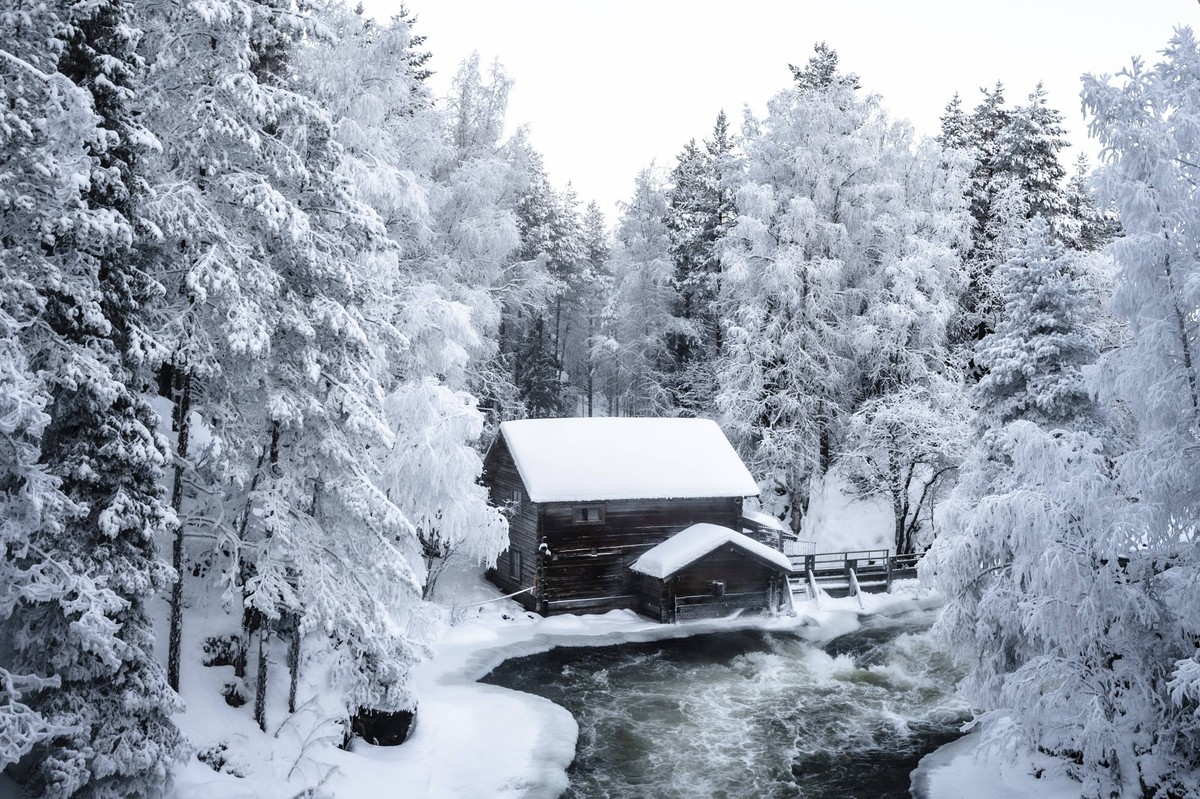 Verschneite Hütte eingebettet in winterlichen Wald bei gefrorenem Fluss. Kleine Bärenrunde. Finnland. Juuma Snowy hut nestled in a wintery forest with a frozen river. Little bear round. Finland Juuma  ...