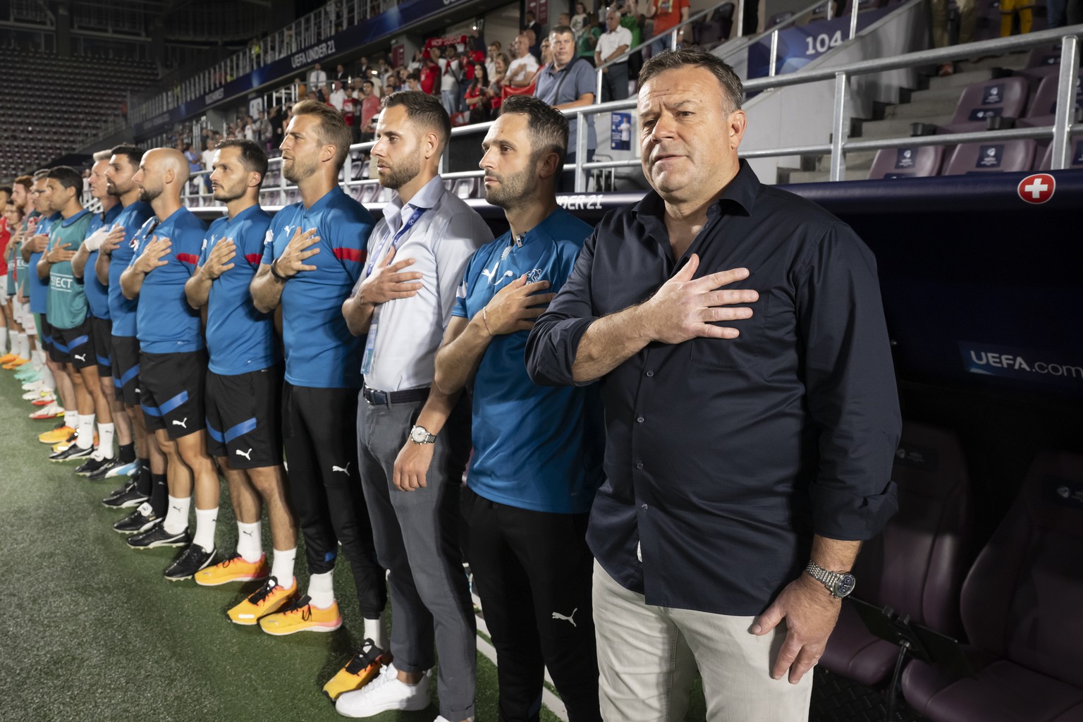 Switzerland&#039;s head coach Patrick Rahmen, right, and staff sing the national anthem, during the quarterfinal match between Spain and Switzerland at the 2023 UEFA European Under-21 Championship tou ...