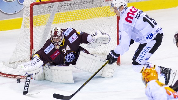 Le joueur du club tessinois, Gregory Hofmann, droite, a la lutte pour le puck avec le gardien du club genevois, Gauthier Descloux, gauche, lors du match du championnat suisse de hockey sur glace de Na ...