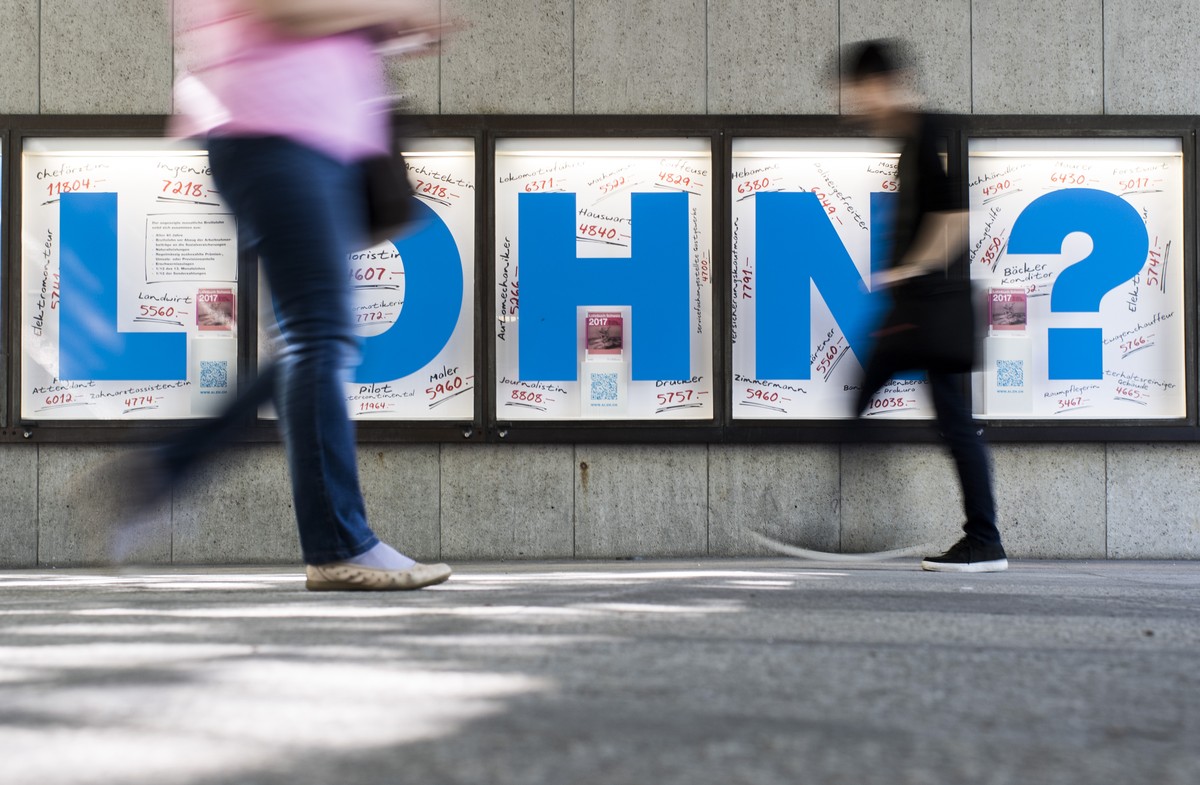 Menschen bewegen sich vor einem Plakat mit der Aufschrift "Lohn?", aufgenommen am Donnerstag, 6. Juli 2017 in Zuerich. (KEYSTONE/Ennio Leanza)