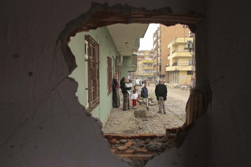 Residents are seen through a hole in a damaged building in the mostly-Kurdish town of Silopi, in southeastern Turkey, near the border with Iraq, Tuesday, Jan. 19, 2016. Turkey&#039;s prime minister an ...