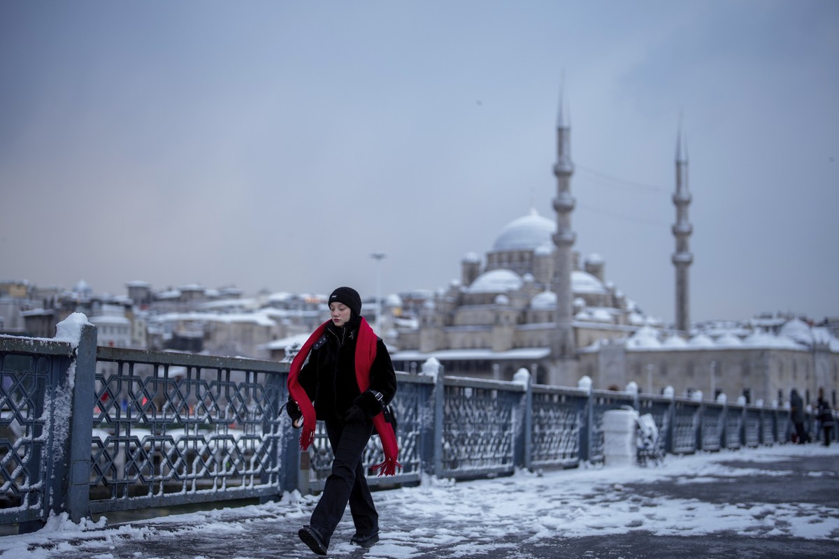 Backdropped by the New mosque, a woman walks on the Galata Bridge after a snowfall in Istanbul, Turkey, Friday, Feb. 21, 2025. (AP Photo/Emrah Gurel)