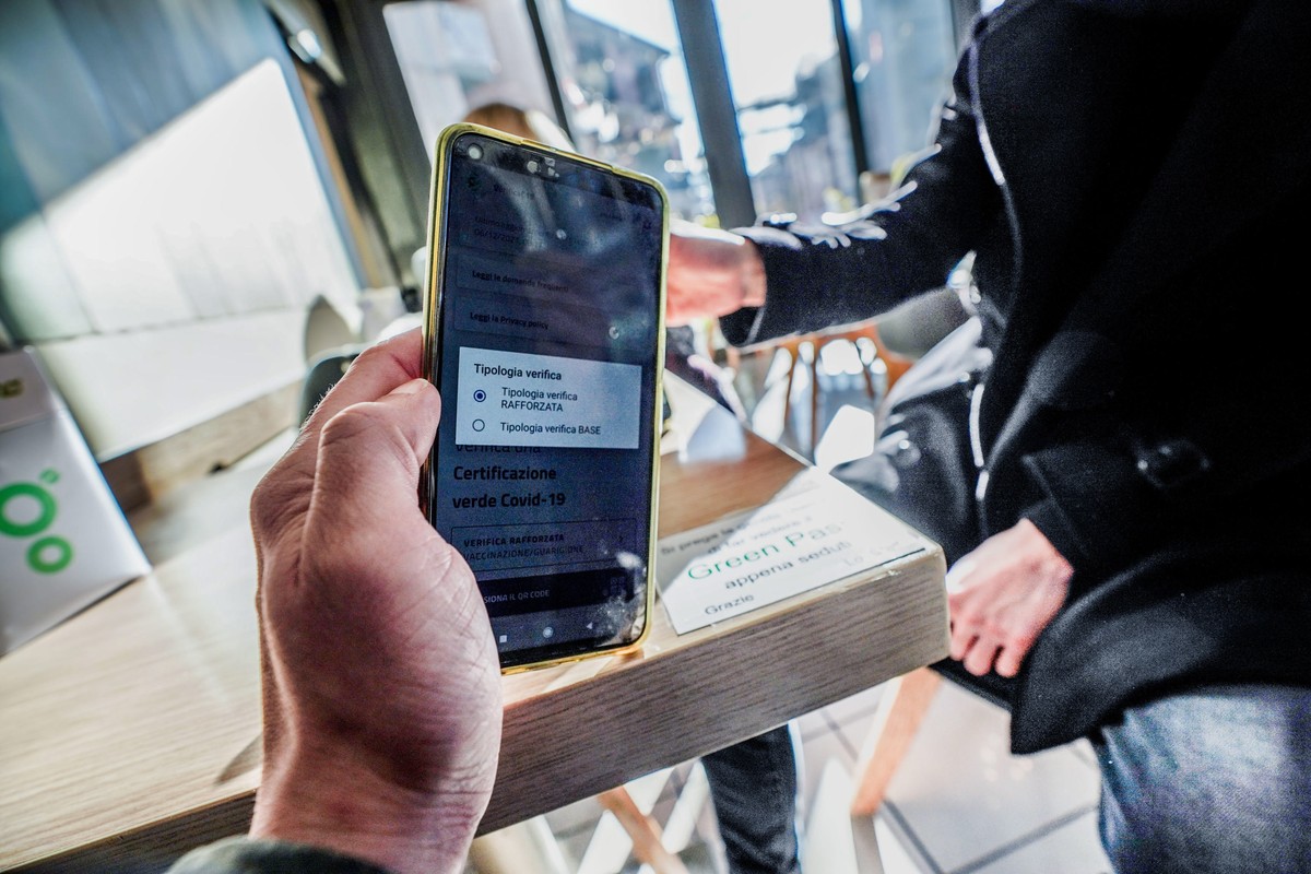 epa09625451 Staff of coffee bar checks the QR code confirming that people received the Covid-19 vaccine, in Milan, Italy, 06 December 2021. The measures on the 'enhanced' green certificate ( ...