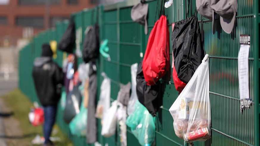 epa08334924 A man take a bag with food and hygiene products donated for Homeless people from a so-called gift fence (lit.: Gabenzaun) in Dortmund, Germany, 31 March 2020. The German government and loc ...