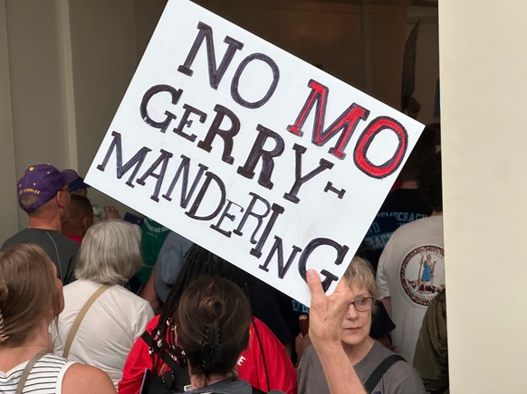 An opponent of a plan to redraw Missouri's U.S. House districts raises a sign against gerrymandering in a hallway outside the state Senate chamber in Jefferson City, Mo., Wednesday, Sept. 10, 202 ...