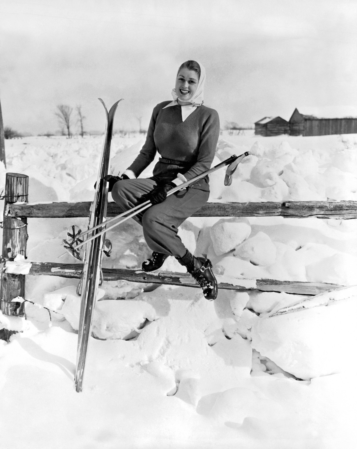 Collingwood, Ontario, Canada c. 1954 A young woman skier takes a break in the sunshine sitting on a split rail fence. PUBLICATIONxINxGERxSUIxAUTxHUNxONLY xUnderwoodxArchives 3-Sport-Ski_19 990_16_3-Sp ...