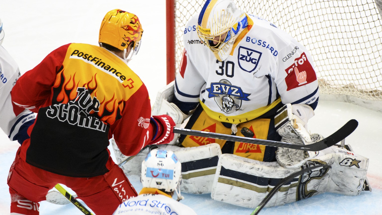 Le top Scorer PostFinance lausannois Denis Malgin, gauche, lutte pour le puck avec le gardien zougois Leonardo Genoni, droite, lors du match a huis clos du championnat suisse de hockey sur glace de Na ...