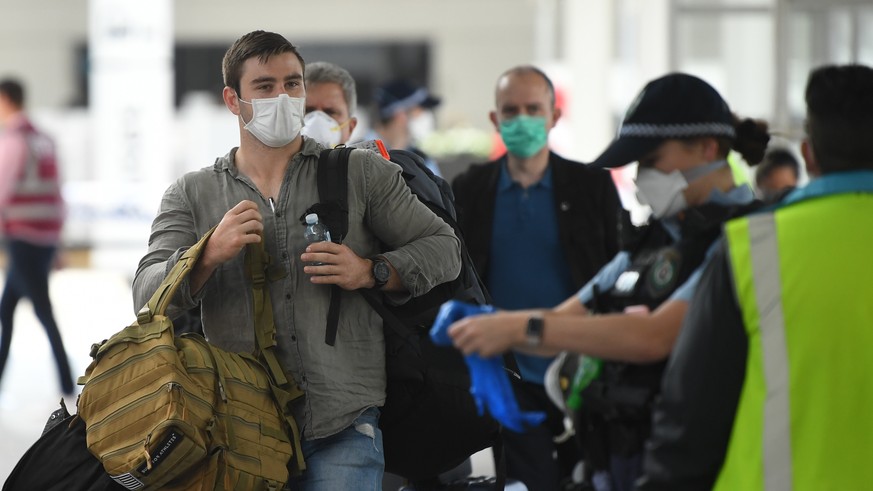 epa08329641 Returning overseas travellers are ushered towards waiting buses for the beginning of their 14-day quarantine after arriving at Sydney International Airport in Sydney, Australia, 29 March 2 ...