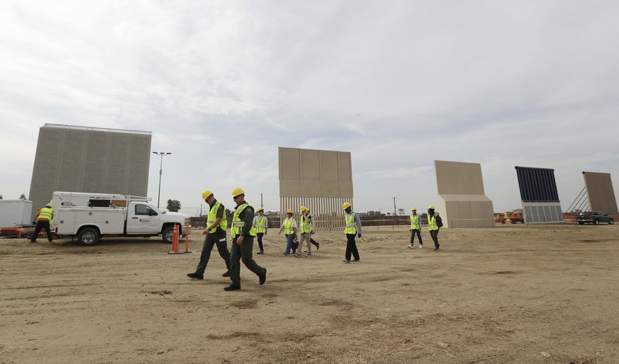 In this Oct. 19, 2017 file photo, people pass border wall prototypes as they stand near the border with Tijuana, Mexico, in San Diego. A U.S. official says recent testing of prototypes of President Do ...