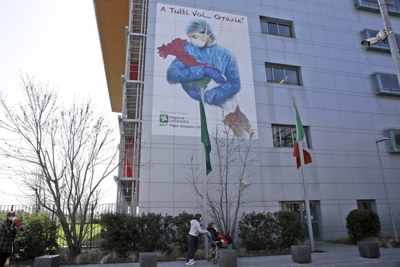 A giant image of a drawing by Venetian artist Franco Rivolli showing a doctor with wings on her back cradling Italy and writing in Italian reading &quot;To all of you... Thank you!&quot;, is displayed ...