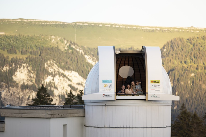 Eine Familie besucht die Sternwarte auf dem Mont Soleil. Die Familie steht im Inneren und schaut nach aussen.