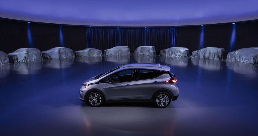 This photo provided by General Motors Co. shows a Chevrolet Bolt, surrounded by nine electric and fuel cell vehicles covered by tarps. On Monday, Oct. 2, 2017, GM announced the company will produce tw ...