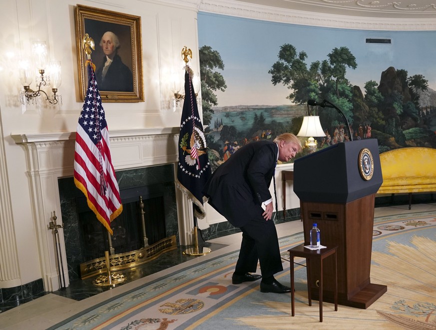 President Donald Trump looks for bottle water as he pauses while speaking about his trip to Asia in the Diplomatic Reception Room of the White House, Wednesday, Nov. 15, 2017 in Washington. (AP Photo/ ...