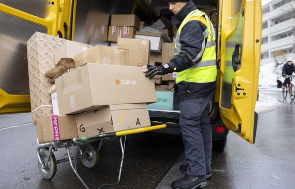 Der Paketbote der Schweizerischen Post Vito Bochicchio liefert Pakete in Zuerich Hoengg, aufgenommen am Dienstag, 5. Dezember 2023 in Zuerich. (KEYSTONE/Michael Buholzer)