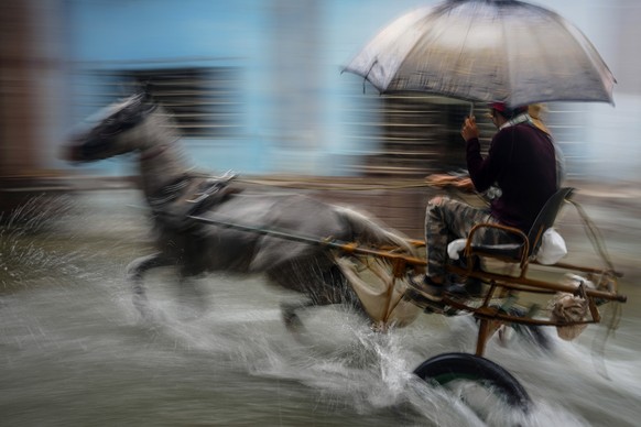 A horse pulls a buggy with passengers through a street flooded by heavy rains, in Havana, Cuba, Friday, June 3, 2022. Heavy rains have drenched Cuba with almost non-stop rain for the last 24 hours as  ...