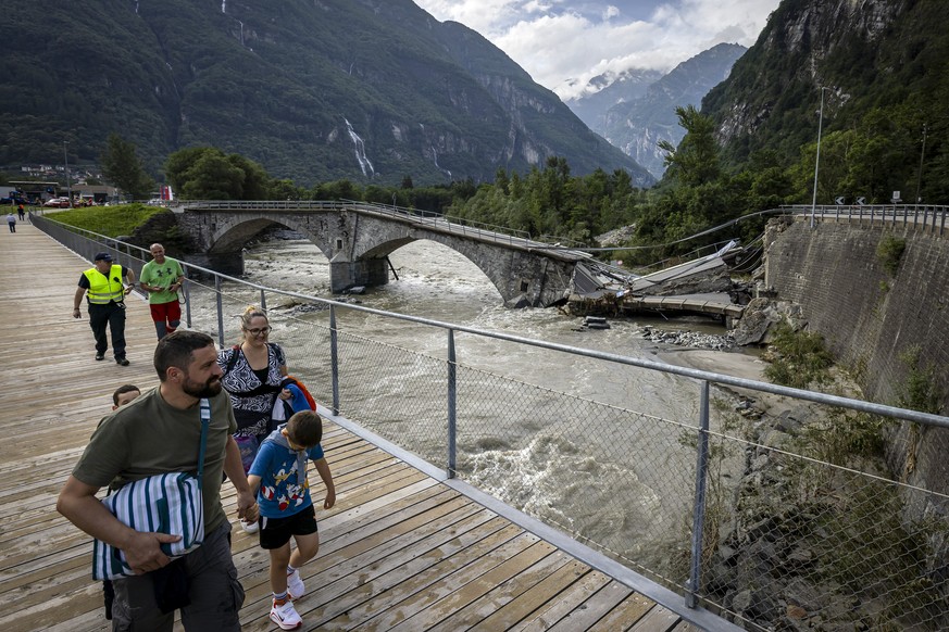 Pedestrians leave Cevio via a pedestrian bridge next to the collapsed Visletto bridge between Visletto and Cevio, in the Maggia Valley, southern Switzerland on Sunday June 30, 2024. The storm in the n ...