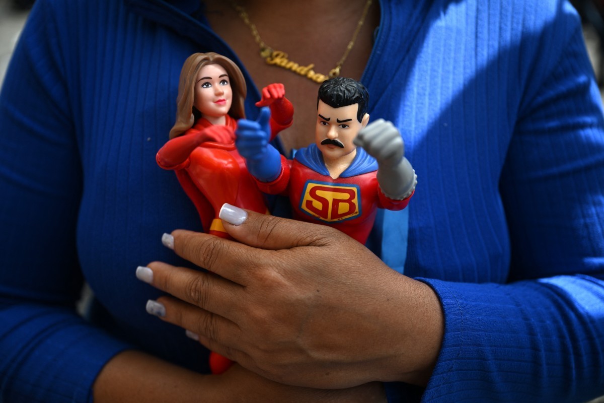 A woman holds toys depicting Venezuela's deposed President Nicolas Maduro and his wife, Cilia Flores, in Caracas on January 3, 2026, after US forces captured Venezuelan leader Nicolas Maduro. Pre ...