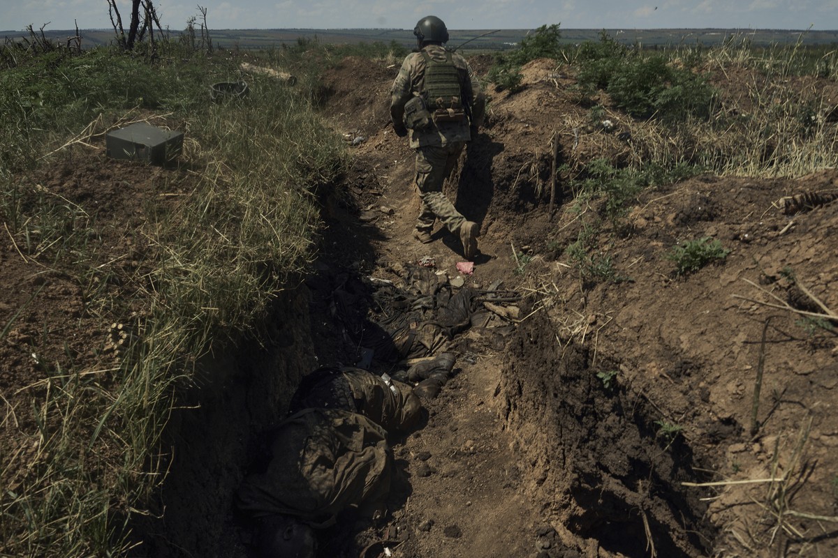 A Ukrainian soldier goes in a recently captured Russian trench with dead Russian soldiers, on the frontline near Bakhmut, Donetsk region, Ukraine, Tuesday, July 4 2023. (AP photo/Libkos)