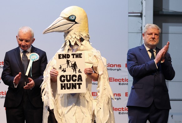 epa12942106 (L-R) Reform UK candidate Gary Neill, Independent candidate Robert Pownall dressed as a Gannet and Scottish National Party Candidate Angus Robertson stand on stand for the declaration of E ...