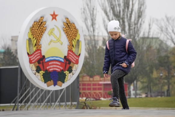 A girl walks past an emblem of the Transnistrian Moldavian Republic in Tiraspol, the capital of the breakaway region of Transnistria, a disputed territory unrecognized by the international community,  ...