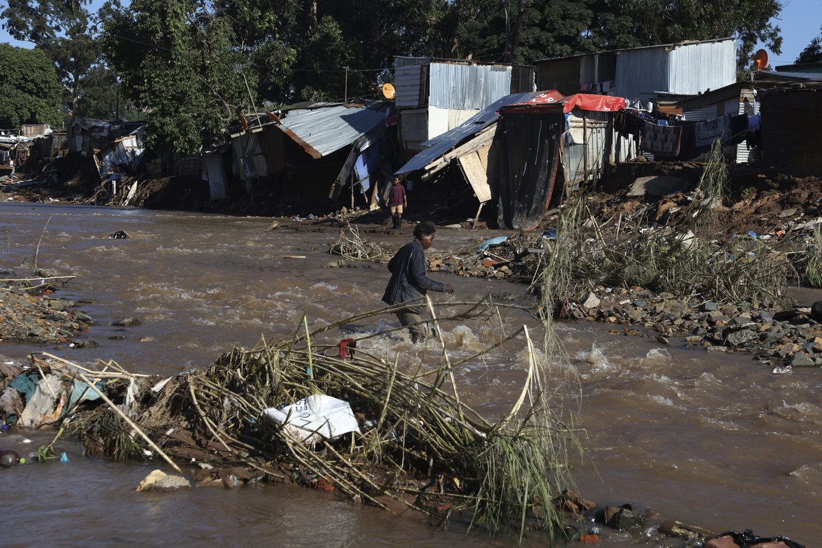 A man crosses a river at an informal settlement during flooding in Durban, South Africa, Thursday, April 14, 2022. Heavy rains and flooding have killed at least 341 people in South Africa's easte ...
