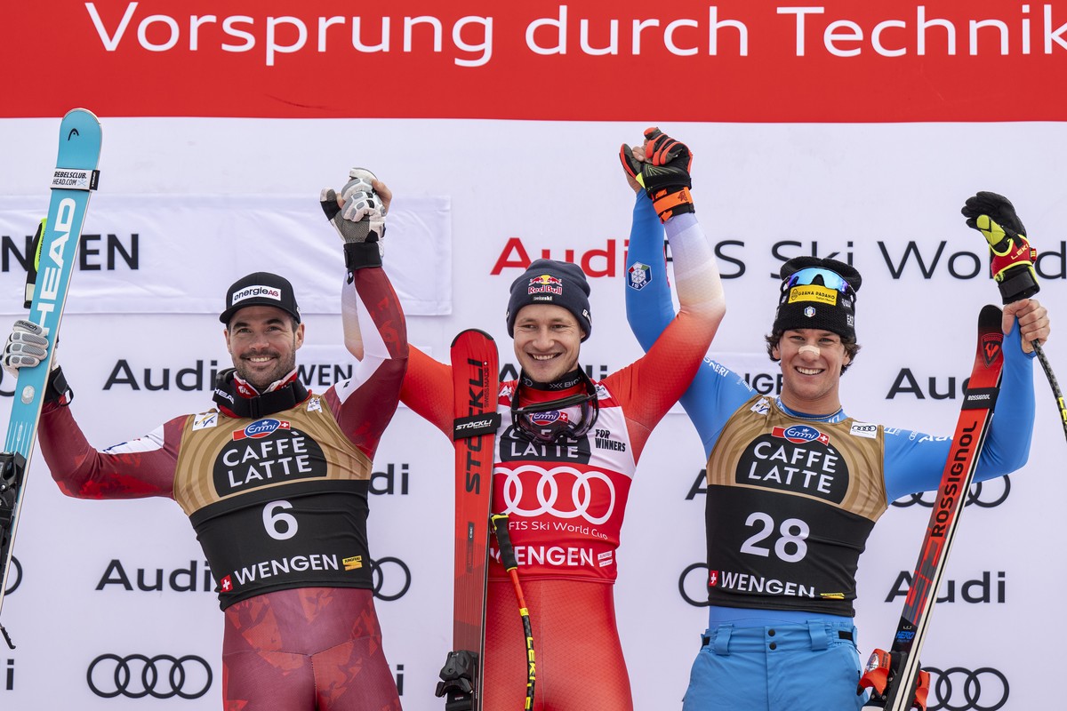 Marco Odermatt of Switzerland, winner, center, Vincent Kriechmayr of Austria, second place, left, and Giovanni Franzoni of Italy, third place, react in the finish area during the men's Downhill r ...