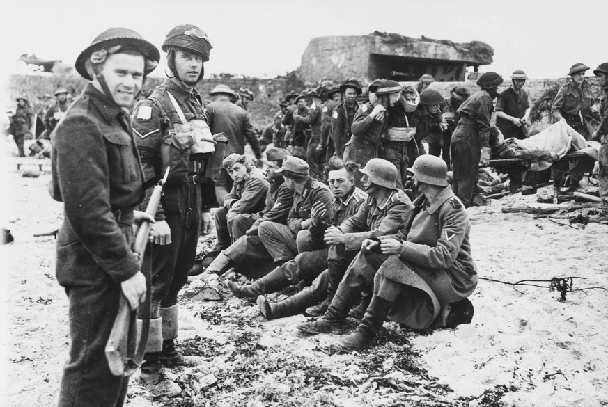 RECORD DATE NOT STATED D-Day - German Prisoners A Canadian picket stands guard over captured German prisoners following the storming of a German defence post two days after D-Day. In the background ca ...
