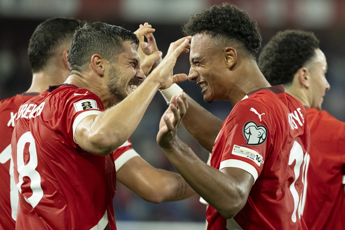 Switzerland's Dan Ndoye, center, celebrates with Remo Freuler, left, after scoring 3-0 during the FIFA 2026 World Cup Group B qualifying soccer match between Switzerland and Slovenia at the St. J ...