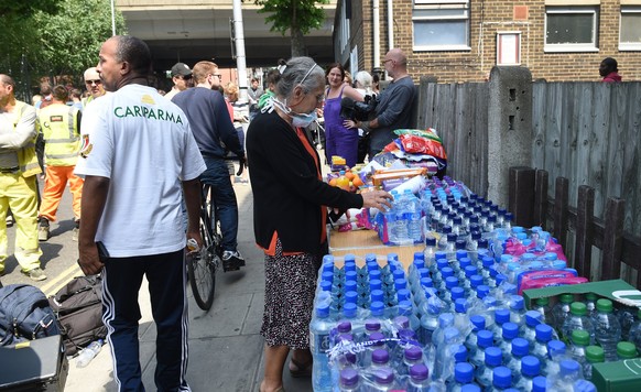 epa06027701 Volunteers bring supplies as flames engulf the nearby Grenfell Tower, a 24-storey apartment block in North Kensington, London, Britain, 14 June 2017. According to the London Fire Brigade ( ...