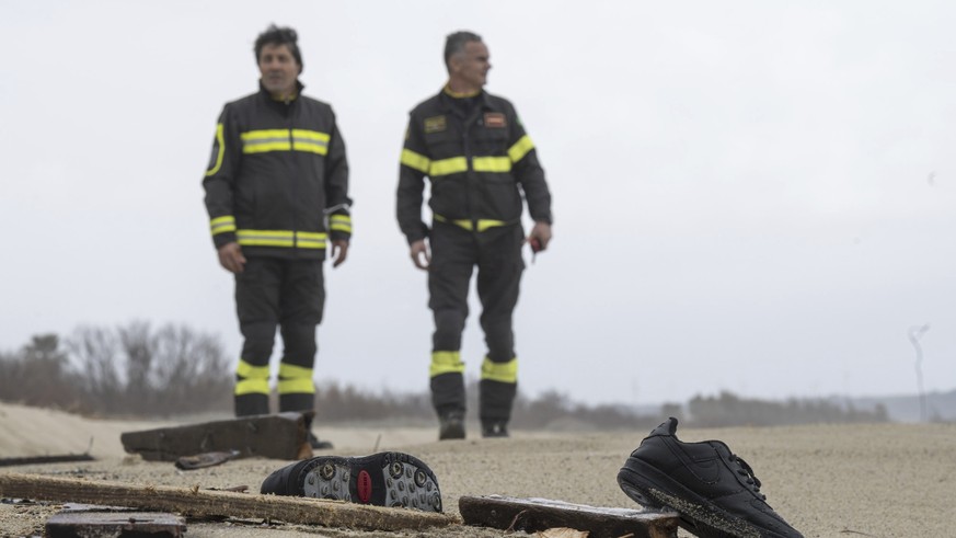 Firefighters look at shoes and debris washed ashore by sea at a beach near Cutro, southern Italy, Monday, Feb. 27, 2023. The death toll has risen to 62 in the migrant tragedy off Italy?s southern coas ...