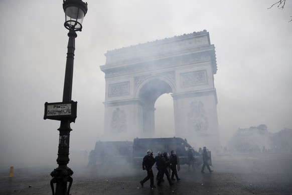 epaselect epa07202665 French riot police pass by the Arc de Triomphe as they clash with protesters wearing yellow vests (gilets jaunes) during a demonstration over high fuel prices on the Champs Elyse ...