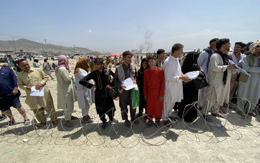 epa09417787 Afghans including those who worked for the US, NATO, Europe Union and the United Nations in Afghanistan wait outside the Hamid Karzai International Airport to flee the country, after Talib ...