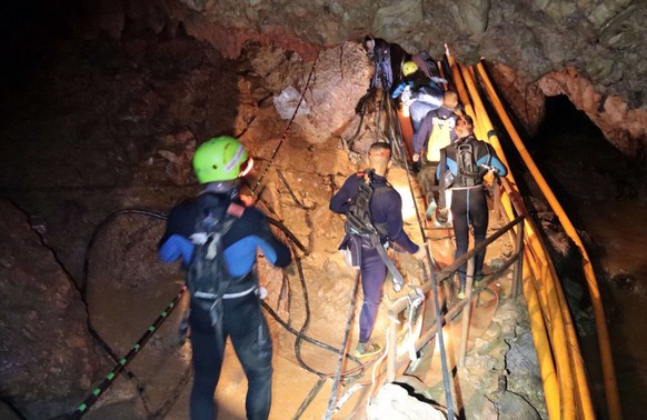 In this undated photo released by the Royal Thai Navy on Saturday, July 7, 2018, members of the Thai rescue team walk into a cave where 12 boys and their soccer coach have been trapped since June 23, in Mae Sa…