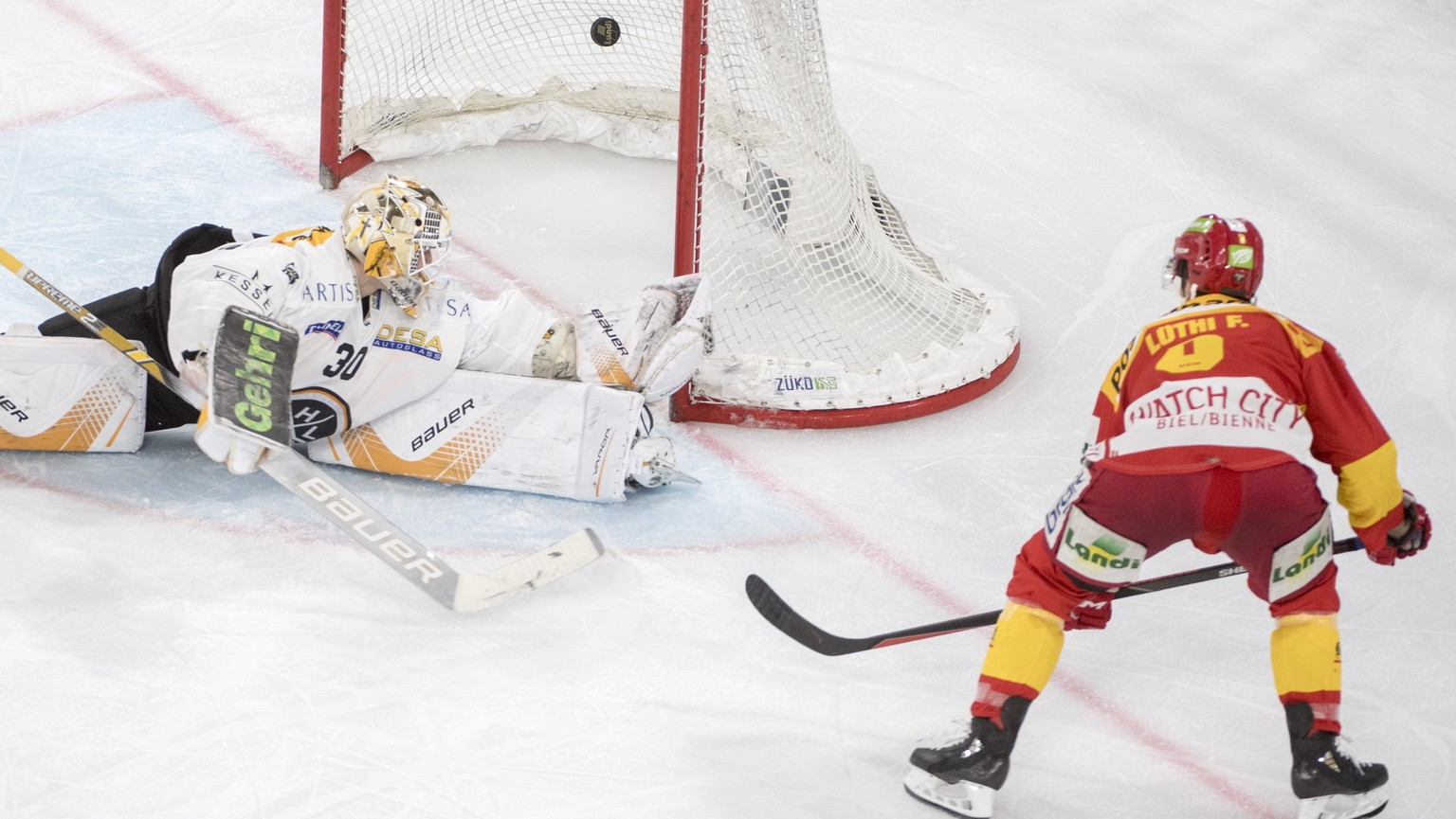 Biels Fabian Luethi, rechts, erziehlt das 3-0 gegen Luganos Goalie Elvis Merzlikins, links, im dritten Playoff-Halbfinalspiel der Eishockey National League zwischen dem EHC Biel und dem HC Lugano, am  ...