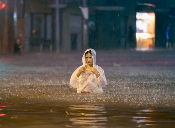 epa11679847 A resident wades on a flooded road in Las Pinas city, Metro Manila, Philippines, 24 October 2024. Tropical Storm Trami has caused floods and damage to infrastructure and properties in the  ...