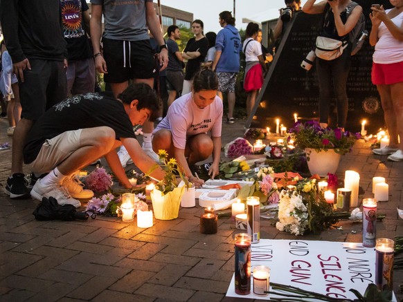 Dozens of mourners gather for a vigil near Central Avenue and St. Johns Avenue in downtown Highland Park, one day after a gunman killed at least seven people and wounded dozens more by firing an AR-15 ...