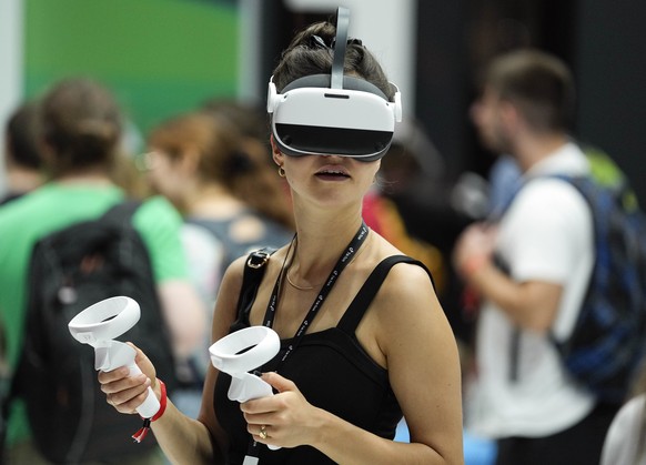 A visitor checks out a fitness video game with a virtual reality gadget at the Gamescom computer gaming fair in Cologne, Germany, Thursday, Aug. 25, 2022. Around 1,100 exhibitors from 53 countries exp ...