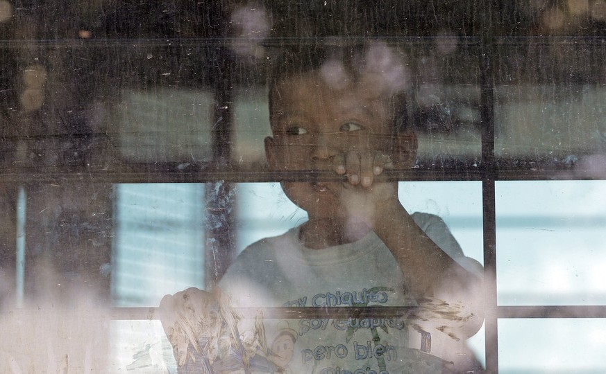 An immigrant child looks out from a U.S. Border Patrol bus leaving as protesters block the street outside the U.S. Border Patrol Central Processing Center Saturday, June 23, 2018, in McAllen, Texas. A ...