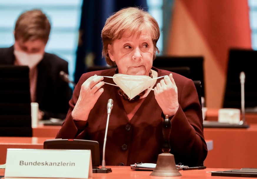 epa09064884 German Chancellor Angela Merkel puts off her face mask as she attends the weekly meeting of the German Federal cabinet in the conference hall of the Chancellery in Berlin, Germany, 10 Marc ...