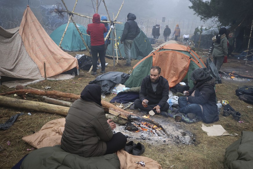 Migrants from the Middle East and elsewhere warm up at the fire gathering at the Belarus-Poland border near Grodno, Belarus, Thursday, Nov. 11, 2021. The European Union has accused Belarus&#039; autho ...