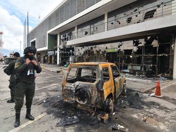 epa07991612 Bolivian police observe the destruction at a police station that groups of protesters vandalized in Cochabamba, Bolivia 12 November 2019, after the resignation of Evo Morales, while in La  ...