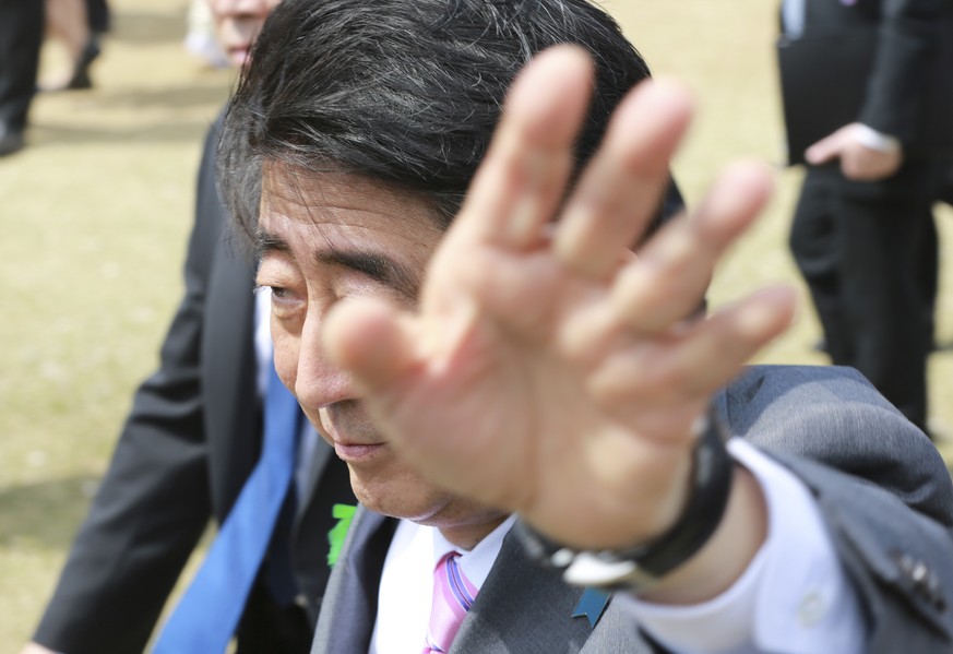 Japanese Prime Minister Shinzo Abe waves to the guests during a cherry blossom viewing party hosted by Abe at Shinjuku Gyoen National Garden in Tokyo, Saturday, April 15, 2017. (AP Photo/Eugene Hoshik ...