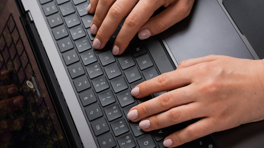 Frau am Laptop, Finger auf Tastatur. Symbolbild.
